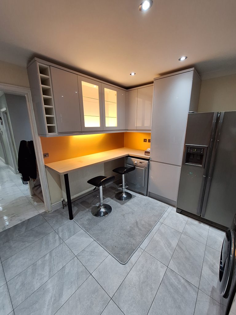 Gloss kitchen with breakfast bar and warm splashback