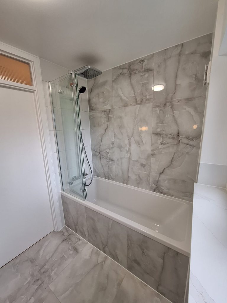 Bath and glass shower screen with marble-effect tiling