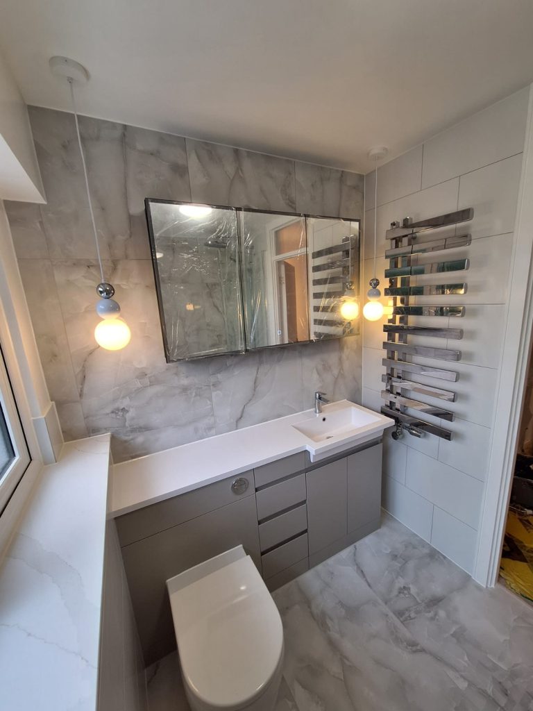 Grey fitted vanity with pendant lights and chrome towel radiator