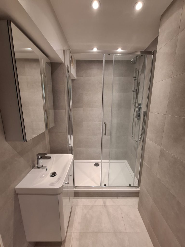 Tiled shower room with glass enclosure and white vanity